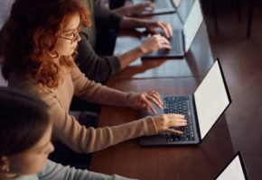 High angle view of high school students studying over laptops on a class at school. Focus is on redhead girl.